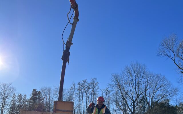 Worker in safety vest stands on scaffolding by concrete formwork.