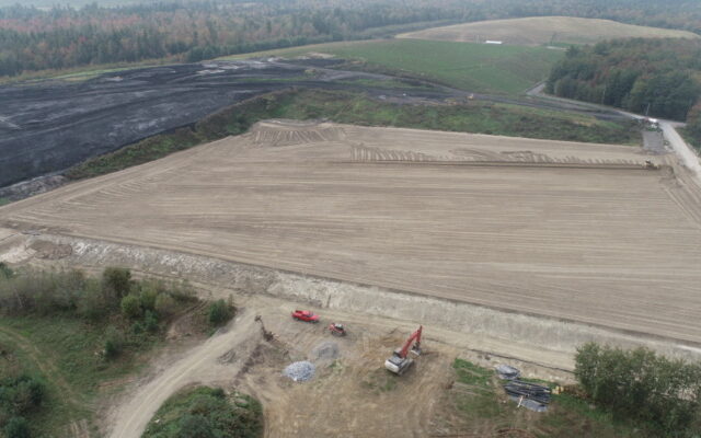Aerial view of construction site with machinery, trees, and excavation.