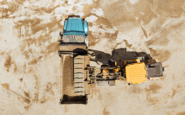 The image shows an aerial view of heavy machinery engaged in moving or processing material on a construction site.