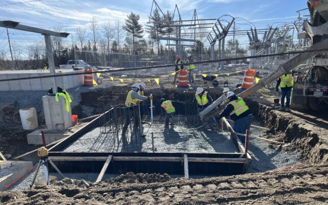 Workers pour and level concrete in rebar-reinforced foundation.