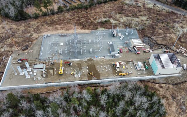 Aerial view: substation site with vehicles, equipment, and trees.