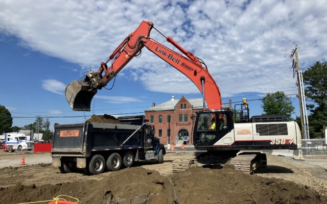 Excavator loading dirt into dump truck at construction site.