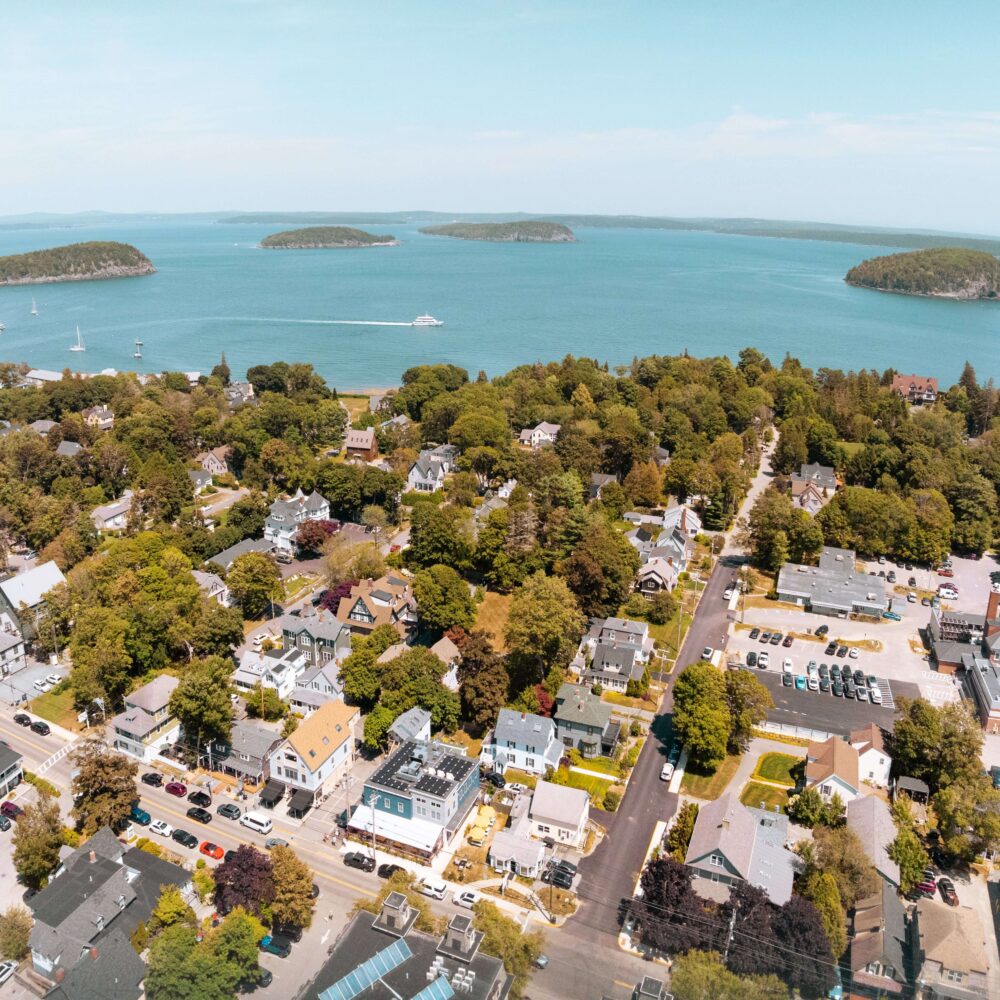 Coastal town, trees, buildings, parked cars, and offshore islands.