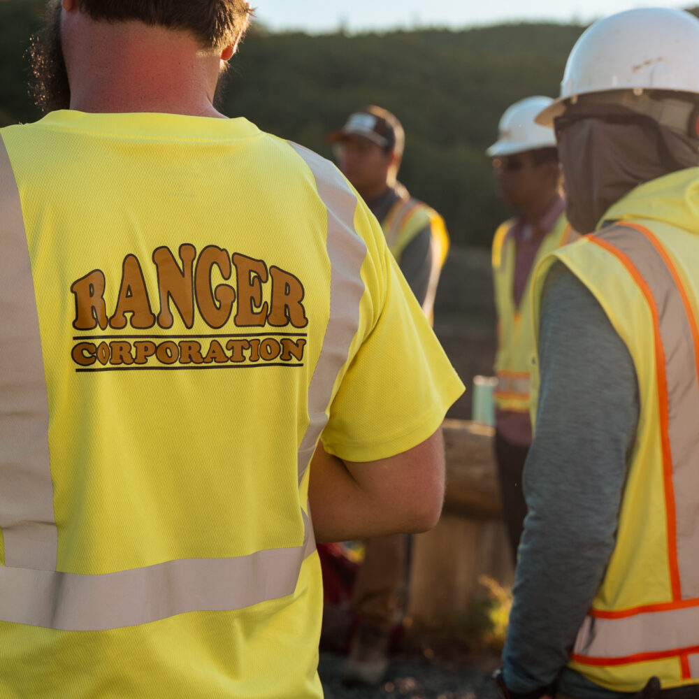 Workers in high-visibility Ranger shirts and safety gear outdoors.