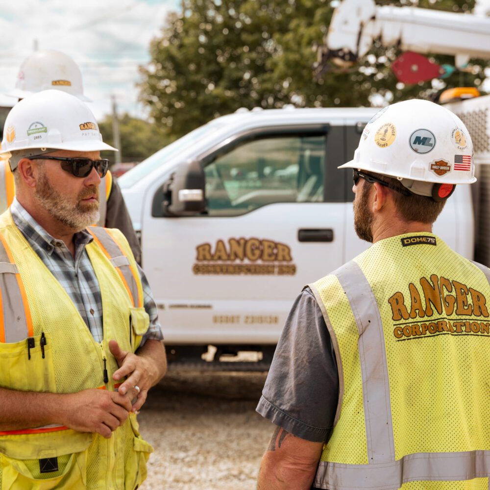 Two construction workers talk at a job site near Ranger truck.