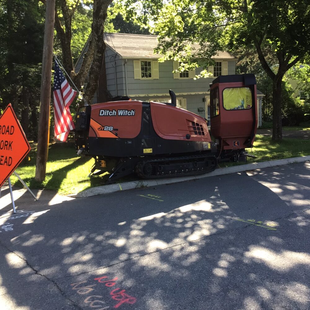 Ditch Witch by Road Work sign and flag on a street.