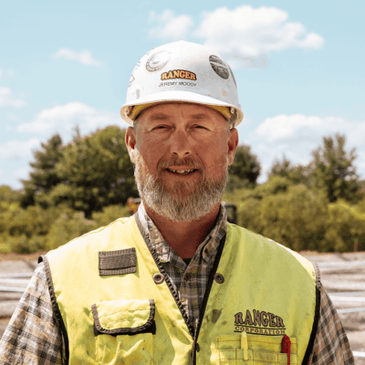 Construction worker in white hard hat and vest outdoors.