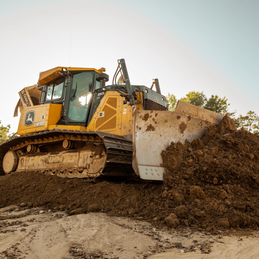 Bulldozer moving dirt at construction site under clear sky.