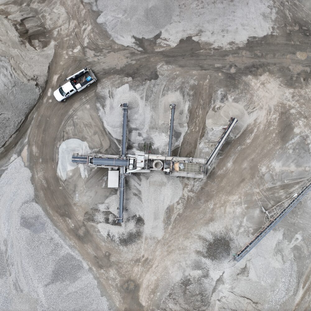 Aerial shot of gravel facility with machinery, truck, and gravel piles.