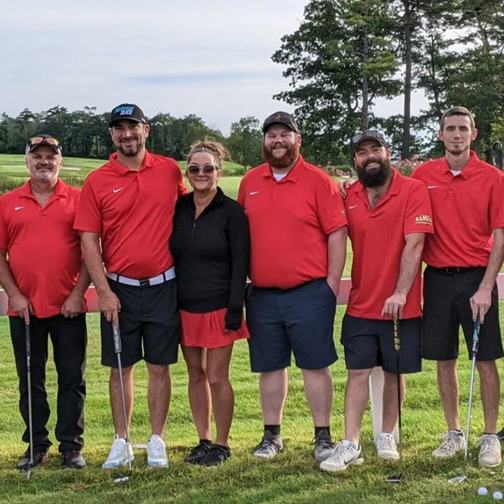 Six golfers, five in red and one in black, smiling together.